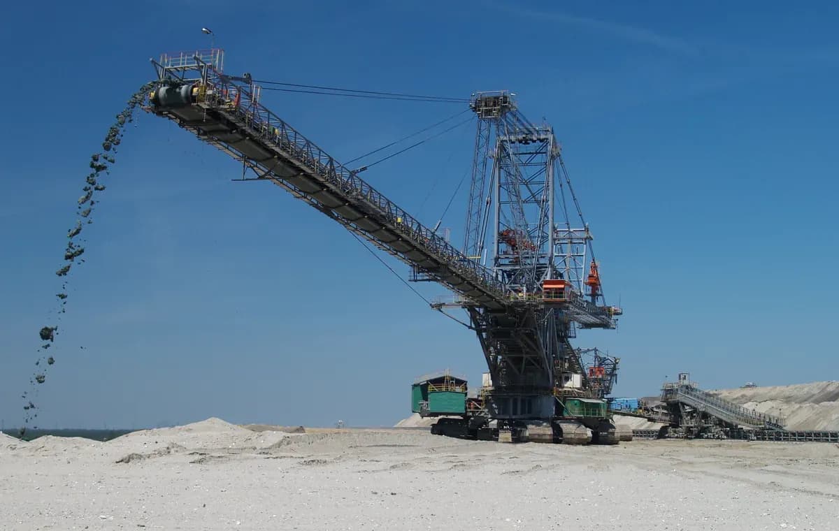 A crawler-mounted spreader on a bench, discharging overburden from the end of its long boom