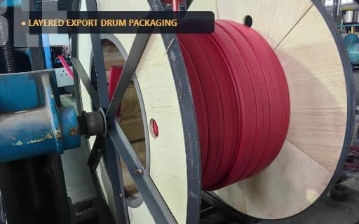 Wooden export drum wound with dark-red flat cable in even layers