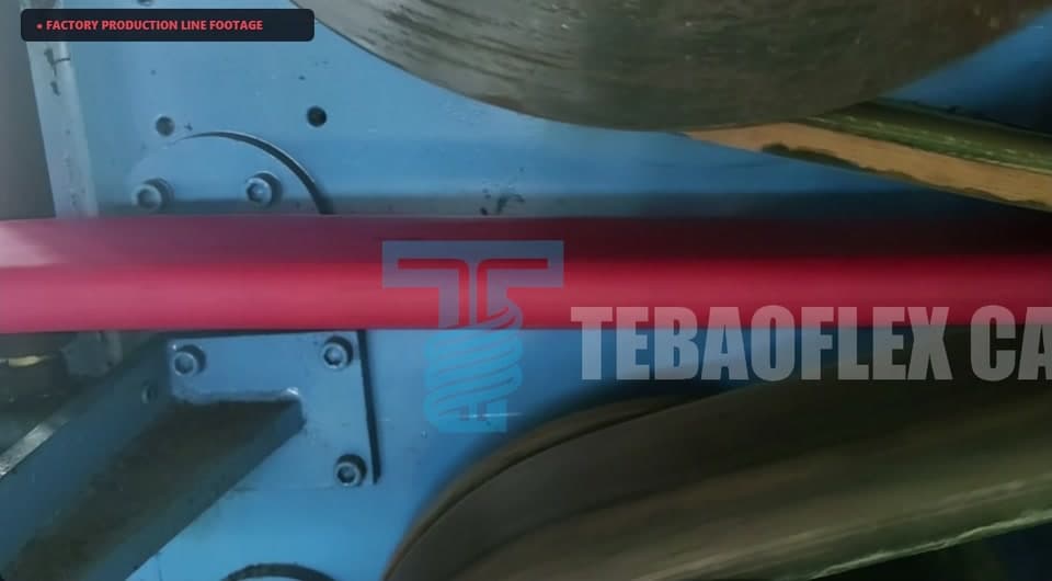 Red flat cable running through the haul-off machine with blue and grey machinery behind it