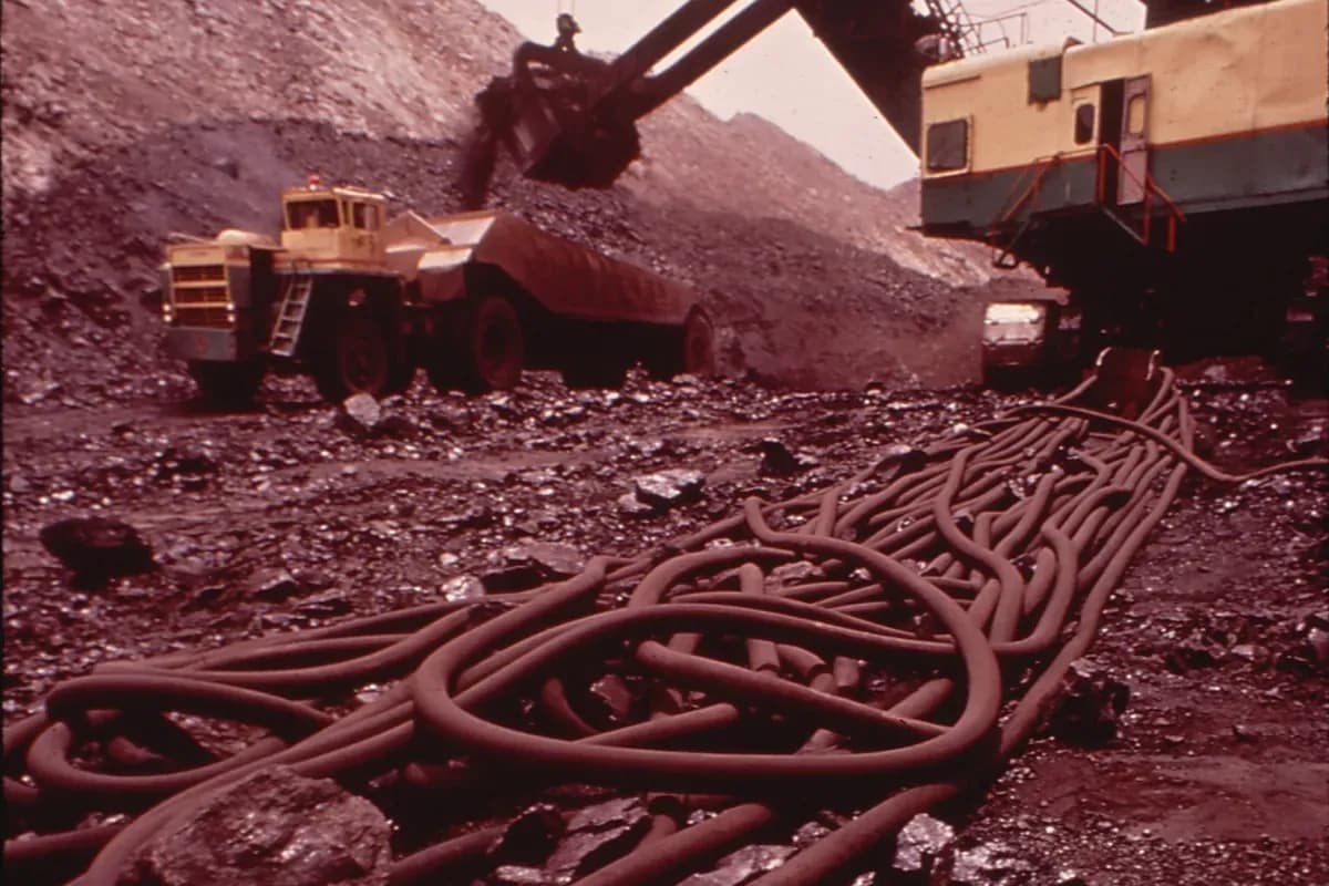 Coils of trailing cable on a mine floor beside an electric shovel loading a haul truck