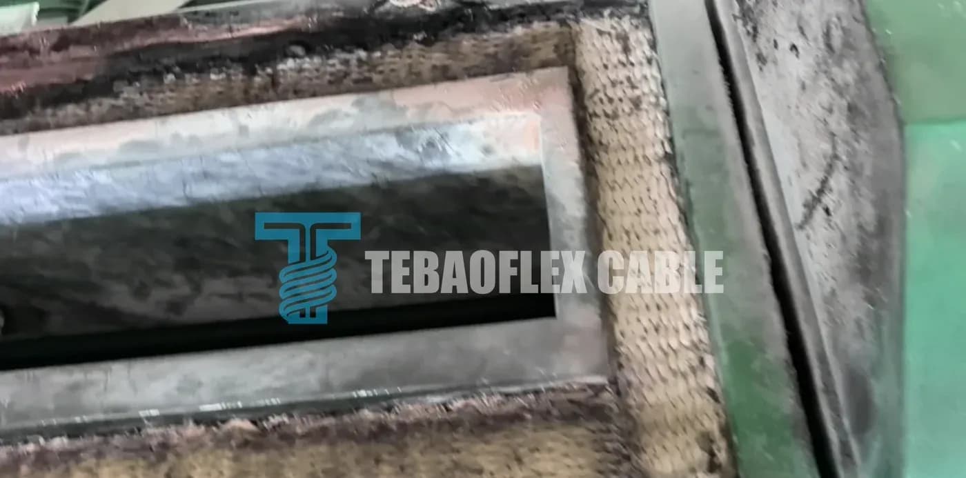 A rectangular aperture framed by tan woven refractory or ceramic-fibre lining, set into a green-painted machine housing.