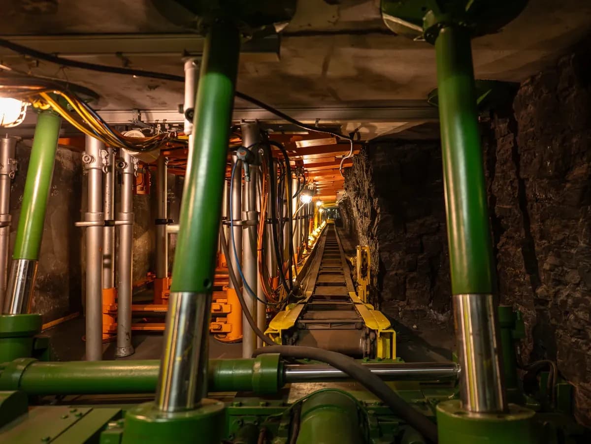 Cables and hoses hanging from the canopies of hydraulic roof supports along a longwall face conveyor